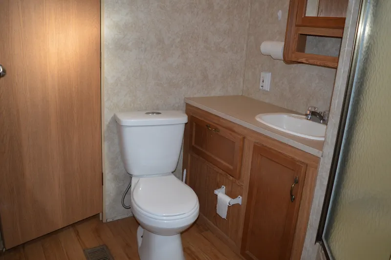 Salle de bain de la roulotte PAC 703 avec toilette, lavabo et douche vitrée